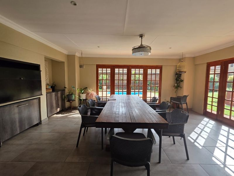 Spacious living area featuring tiled floors, built-in cabinetry, a fireplace, and multiple wooden-framed glass doors providing direct access to the outdoor pool area.