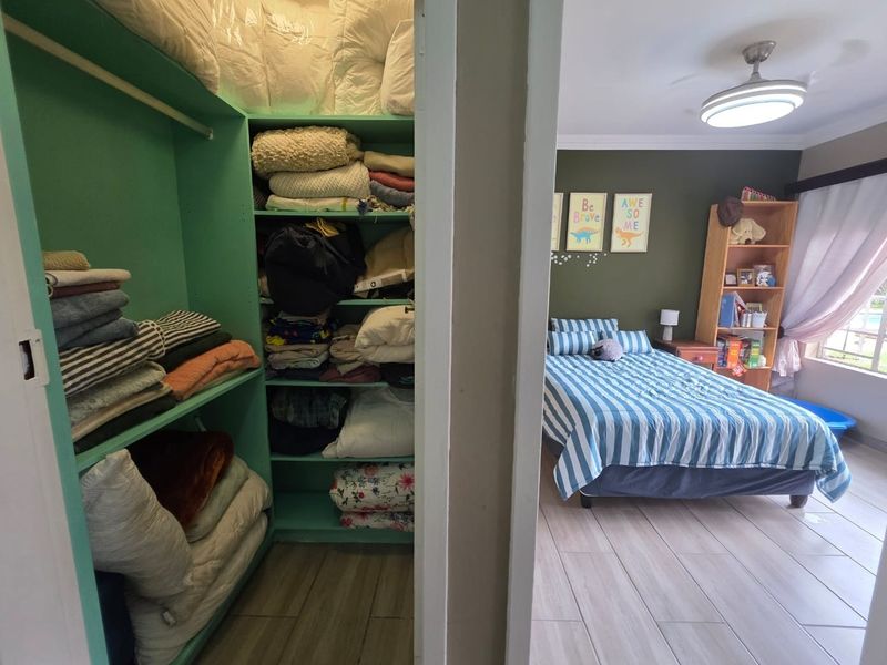 A bedroom featuring tiled flooring, a ceiling fan, and an integrated walk-in closet with built-in shelving.