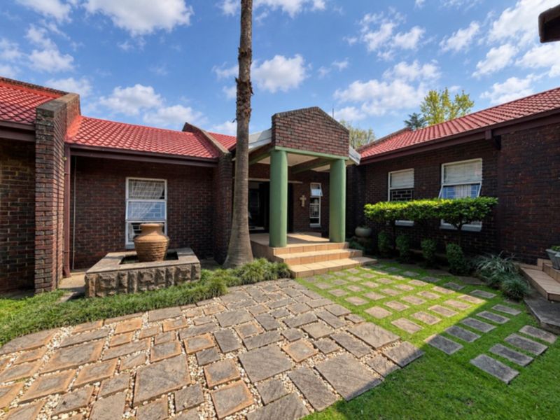 Front entrance of a brick house featuring a covered porch, stone-paved walkway, and a decorative stone water feature.