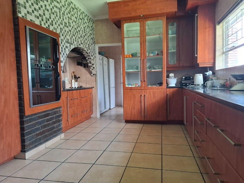 Spacious kitchen featuring wood-finish cabinetry, granite countertops, built-in oven, and a distinctive brick archway feature with tiled flooring throughout.