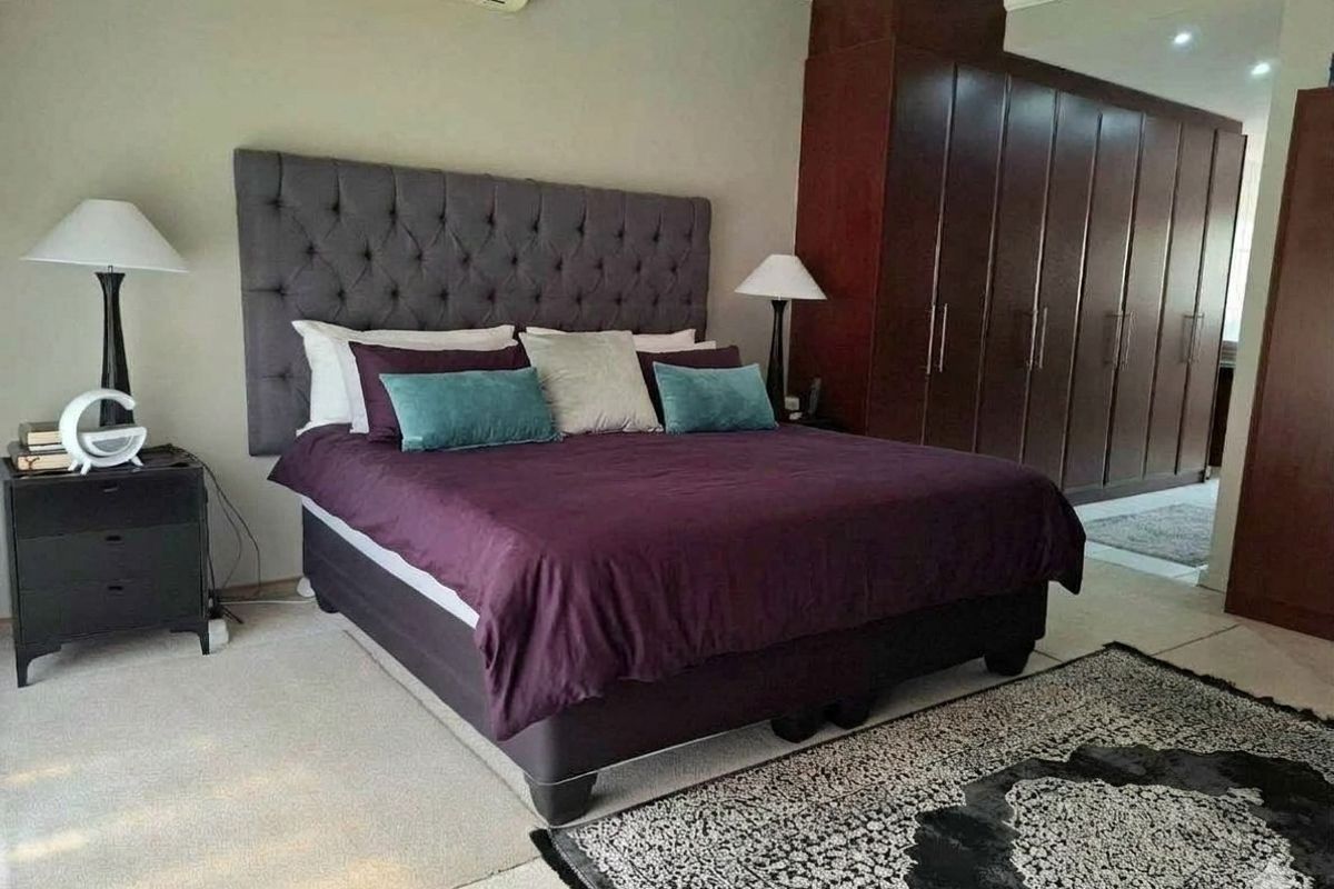 Spacious bedroom featuring extensive dark wood built-in cupboards and a wall-mounted air conditioning unit.