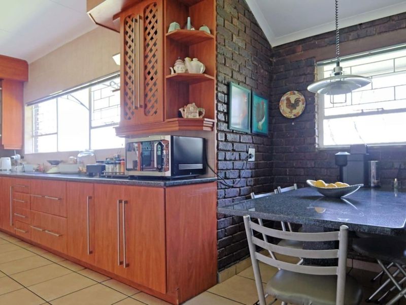 A functional kitchen featuring warm wooden cabinetry, granite countertops, and a distinctive exposed brick wall, providing a rustic yet practical cooking and dining space.
