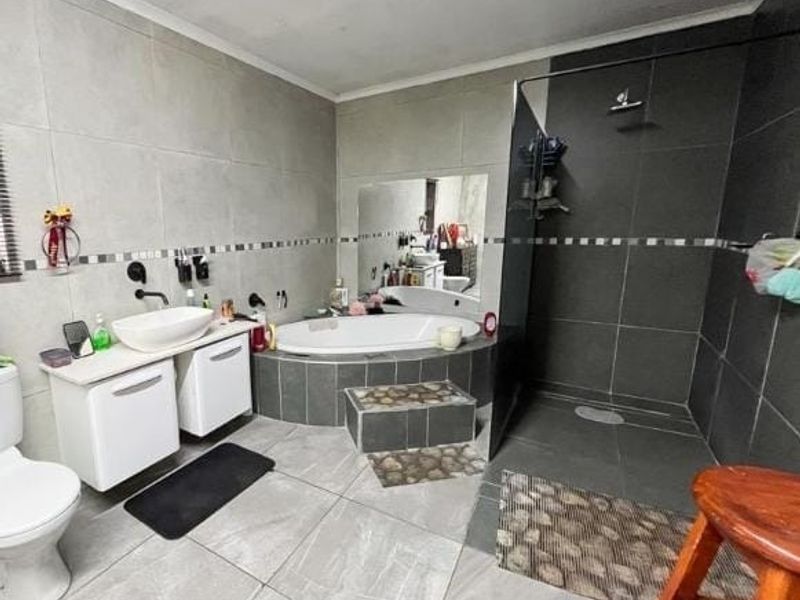 Modern bathroom featuring a built-in bathtub, a spacious walk-in shower with a glass screen, and a wall-mounted vanity with a vessel sink.