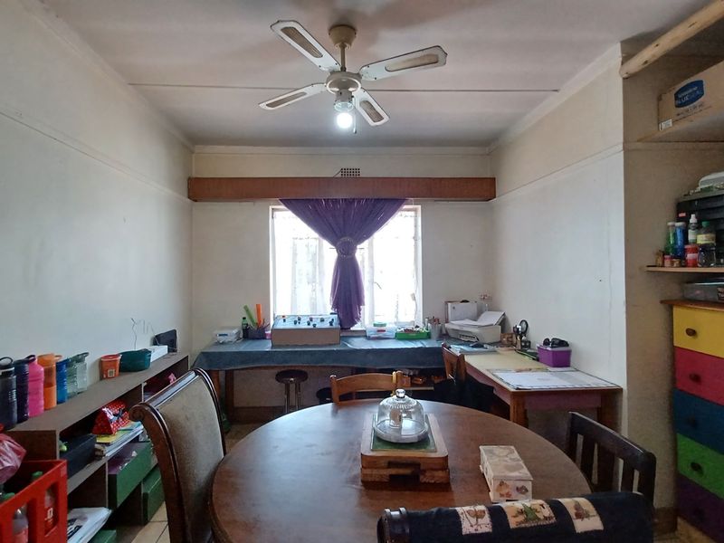 A functional dining room featuring a ceiling fan, built-in shelving, and a window, offering a versatile space for dining or home office use.