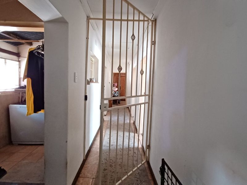 A functional hallway featuring a security gate and tiled flooring, providing access to adjacent rooms including a laundry area.