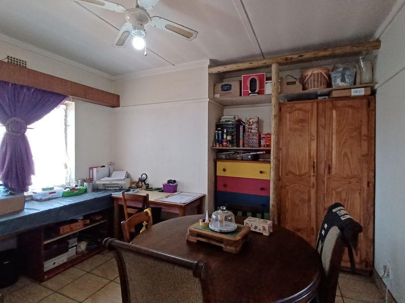 A living area featuring tiled flooring, a ceiling fan, and built-in shelving units, offering a functional space with potential for modernization.