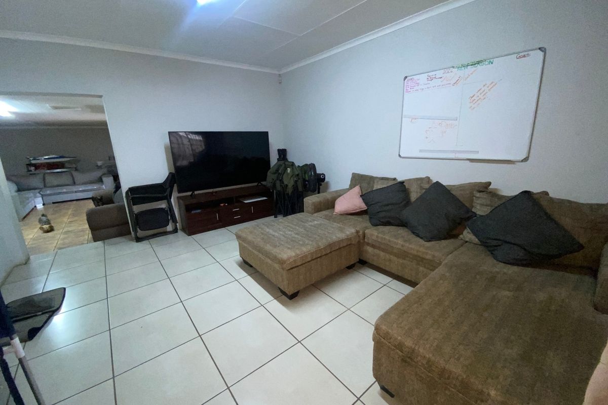 A living room featuring ceramic floor tiles and coved ceiling cornices, providing a functional space with direct access to an adjacent room.
