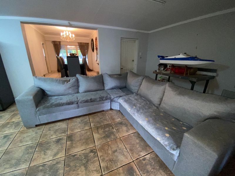 Open plan living area featuring tiled flooring and coved ceilings, with a clear transition into the adjacent dining space.