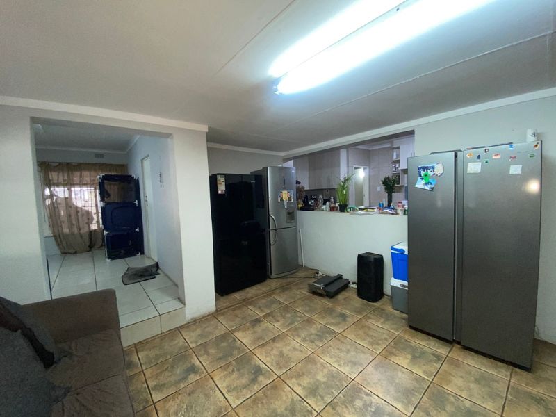 Open plan living area featuring tiled flooring and a pass-through window connecting to the kitchen space.