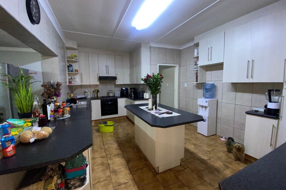 A functional kitchen featuring white built-in cabinetry, a central island with dark countertops, and tiled flooring throughout.