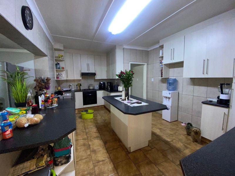 A functional kitchen featuring white built-in cabinetry, a central island with dark countertops, and tiled flooring throughout.
