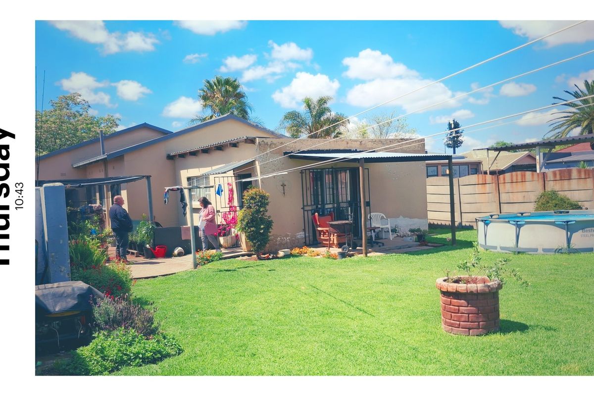 Rear view of the house featuring a covered patio, a well-maintained lawn, and a precast concrete boundary wall.