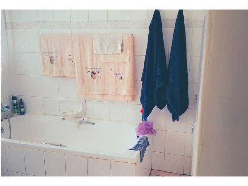 A functional bathroom featuring a built-in bathtub with tiled surround and wall-mounted fixtures.
