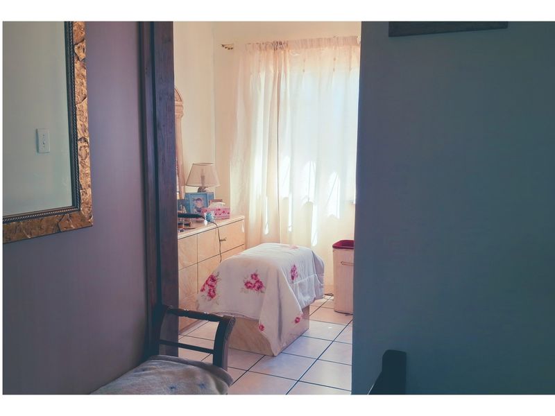 A view into a bedroom featuring tiled flooring and natural light from a window.
