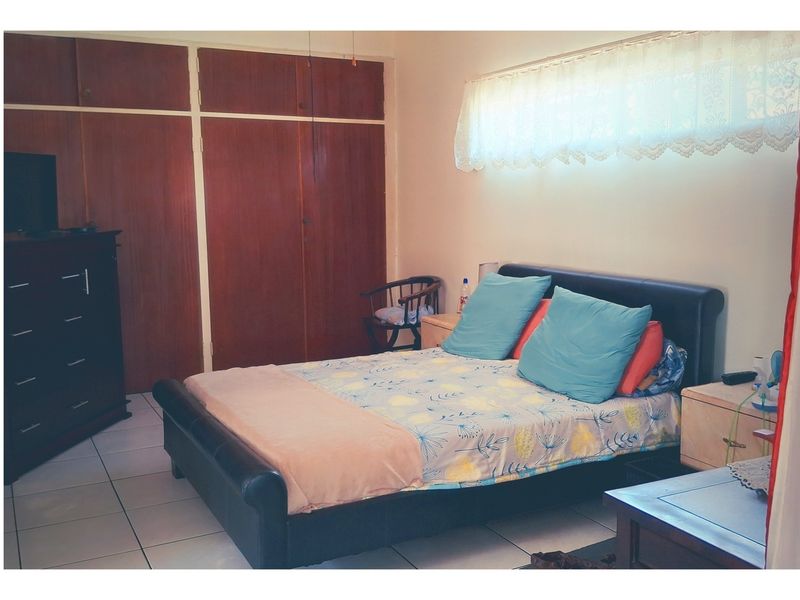 A bedroom featuring built-in wooden cupboards and tiled flooring, offering a functional space with potential for modern updates.