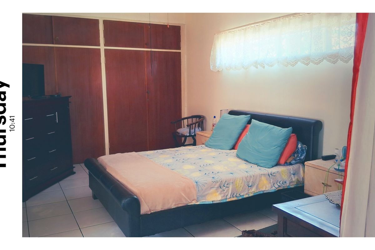 A bedroom featuring built-in wooden cupboards and tiled flooring, offering a functional space with potential for modern updates.
