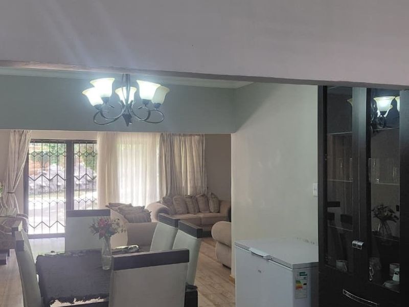 Open plan living and dining area featuring laminate flooring and direct access to the exterior through a security gate.