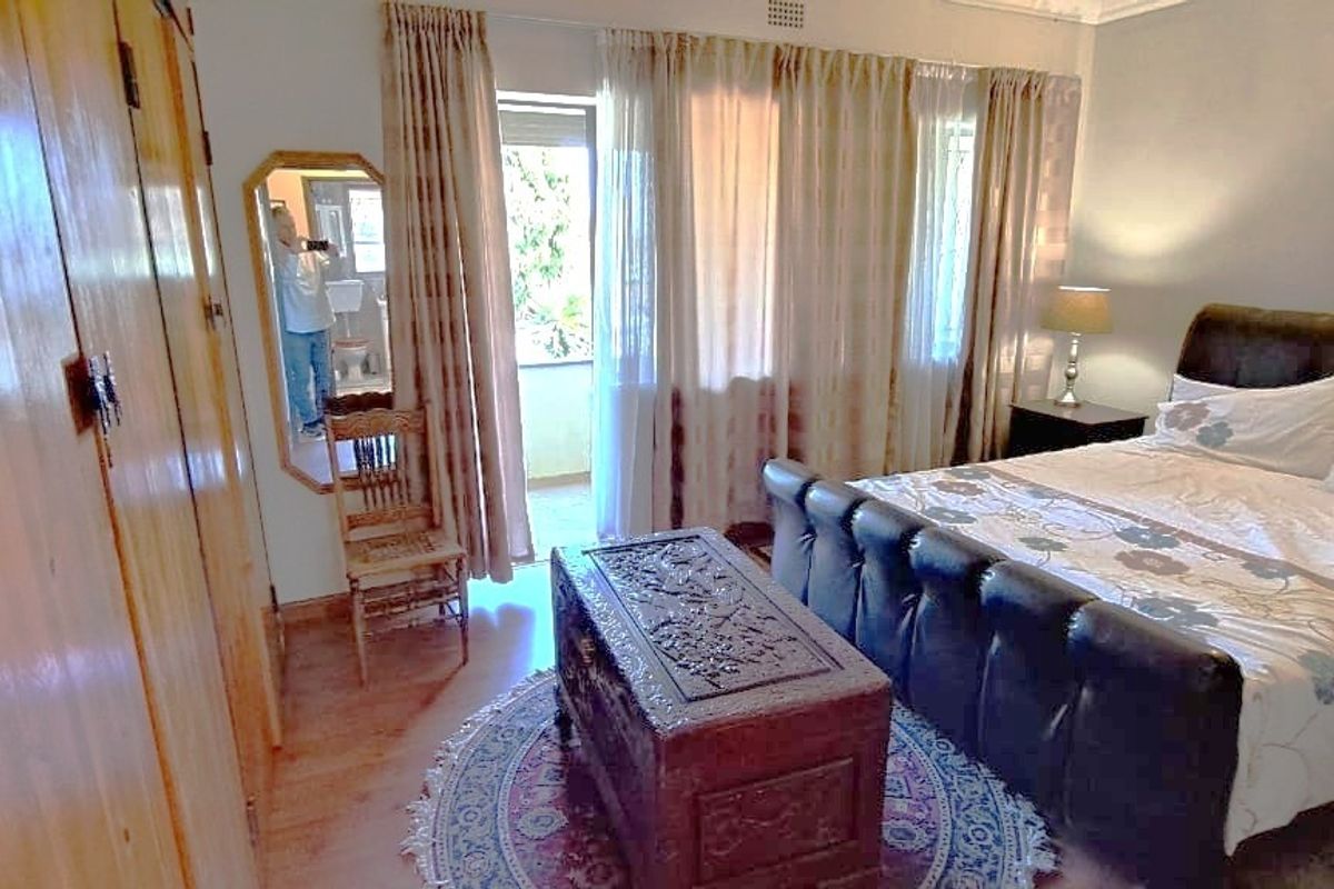 A spacious bedroom featuring built-in wooden cupboards, laminate flooring, and direct access to an outdoor balcony area.