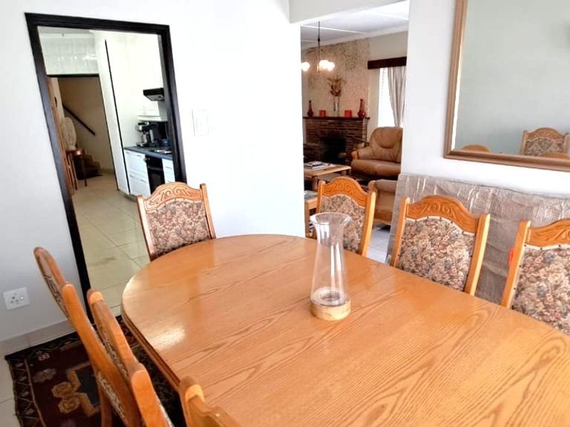 Dining room area featuring tiled flooring and a large wall-mounted mirror, with an open-plan flow leading to the kitchen and living area.