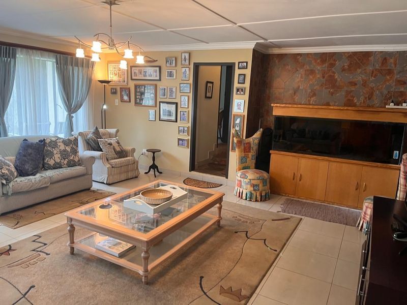 A spacious living room featuring tiled floors, a stone accent wall, and built-in cabinetry, offering a comfortable and functional living space.