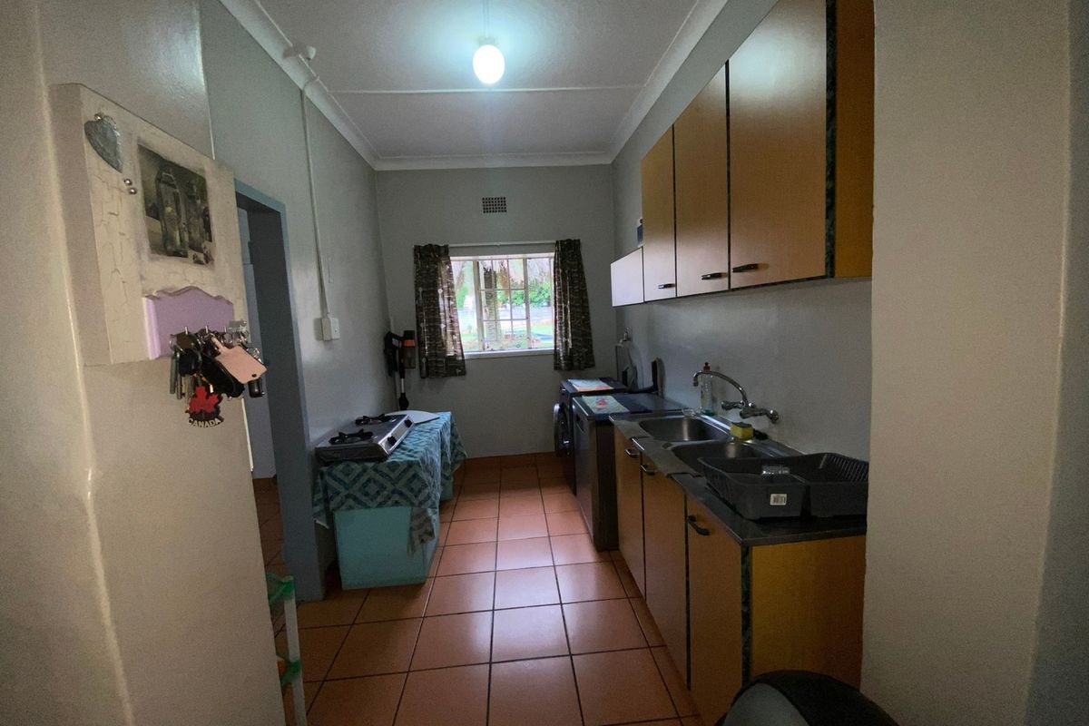 A functional kitchen featuring tiled flooring, built-in cabinetry, and a double bowl sink, offering a practical layout with potential for modern updates.