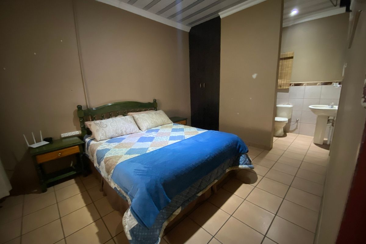 Bedroom featuring tiled flooring, built-in wardrobe, and an open-plan en-suite bathroom with a pedestal basin and toilet.