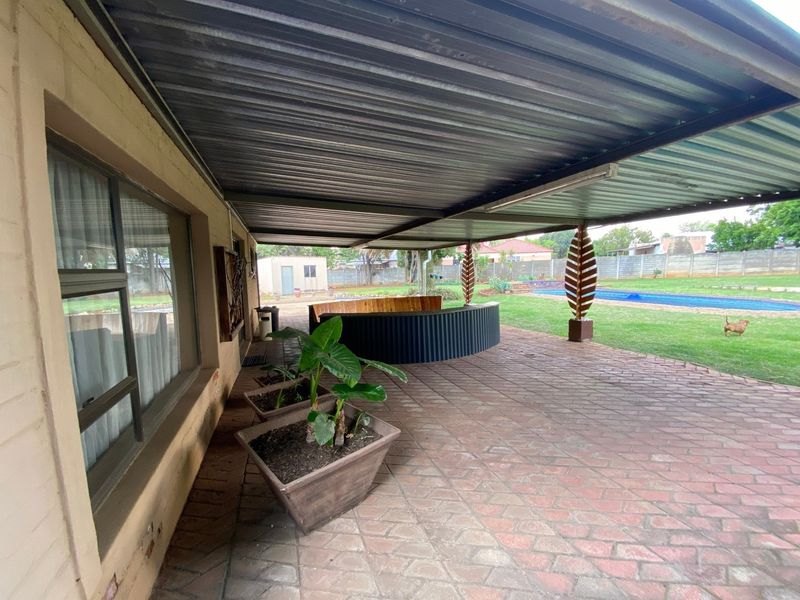 Covered outdoor patio featuring brick paving, a built-in bar counter, and direct access to the garden and swimming pool area.