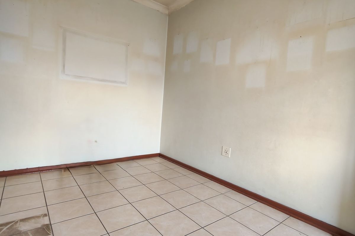 An empty bedroom featuring tiled flooring and walls requiring repainting, offering a blank canvas for renovation and personalization.