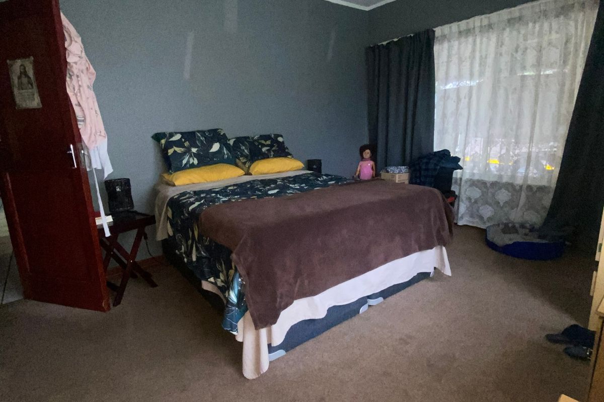 A spacious bedroom featuring a ceiling fan, carpeted flooring, and large windows with curtain rails, offering a blank canvas for potential updates.