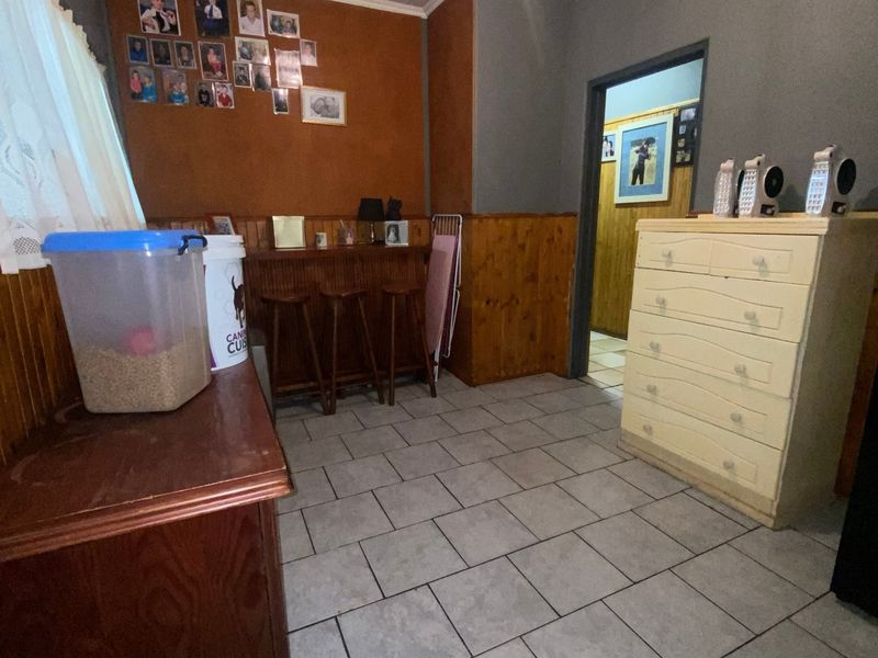 A living area featuring tiled flooring and timber wall paneling, offering a dated aesthetic that could be modernized with updated finishes and paint.