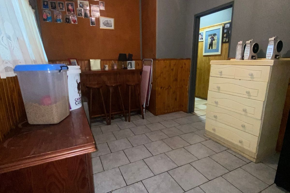 A living area featuring tiled flooring and timber wall paneling, offering a dated aesthetic that could be modernized with updated finishes and paint.