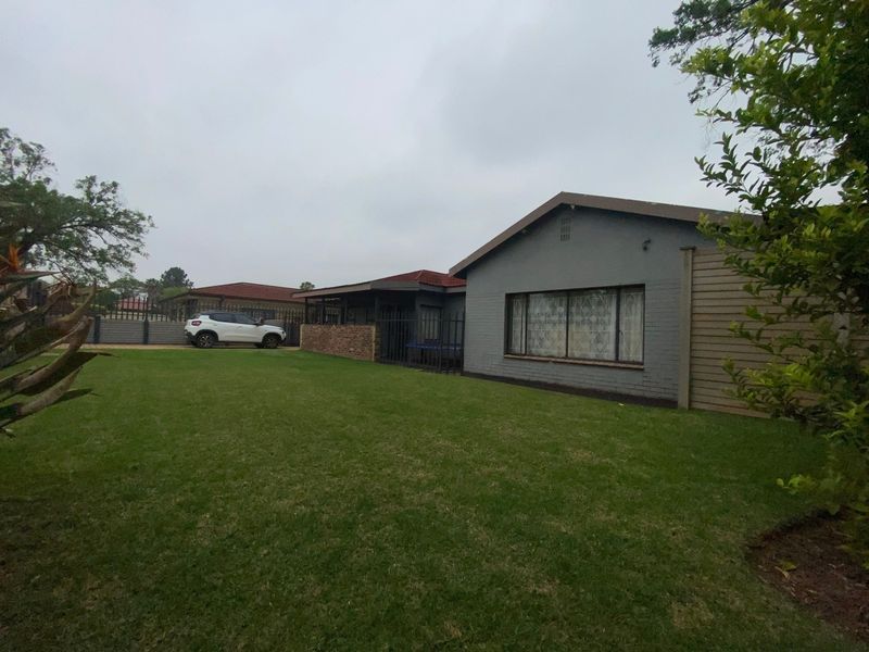 A view of the rear exterior of the house featuring a brick facade, tiled roof, and a well-maintained lawn area.