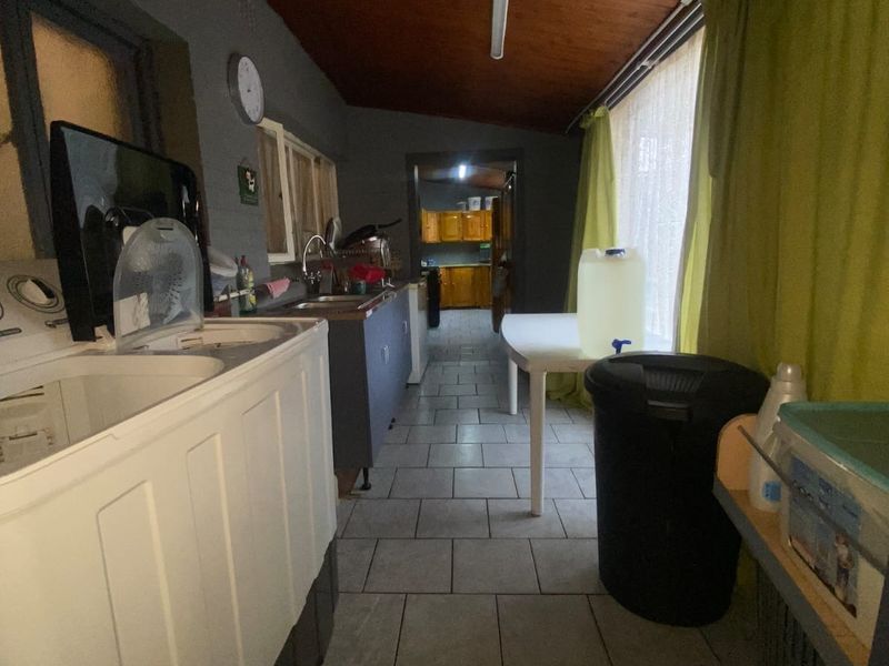 A functional laundry area featuring tiled flooring, a timber ceiling, and a built-in sink, providing practical utility space for the home.
