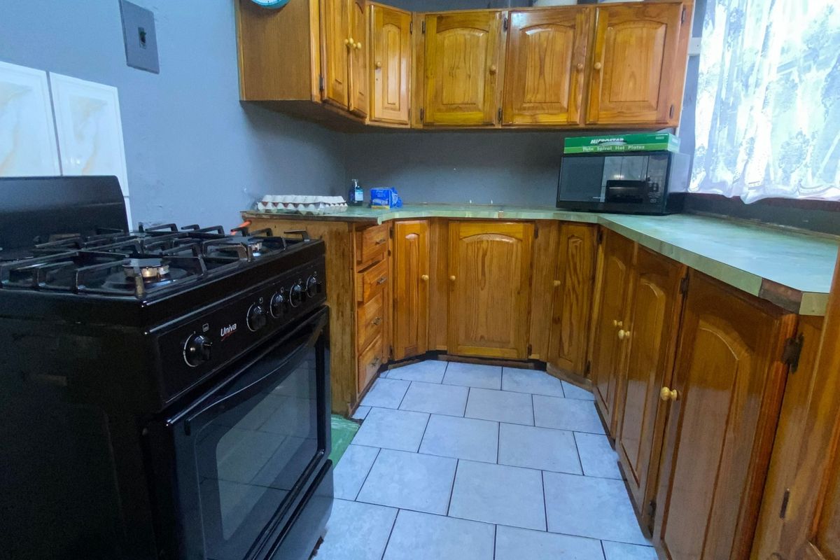 A functional kitchen featuring wooden cabinetry, a gas stove, and tiled flooring, offering a dated aesthetic with potential for modernization.