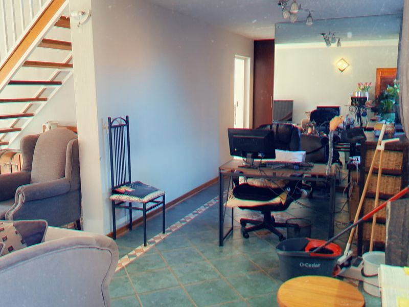 A living area featuring tiled flooring and an open staircase, providing a functional space with potential for modernization.