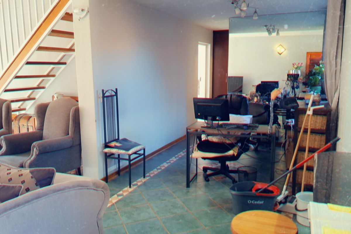 A living area featuring tiled flooring and an open staircase, providing a functional space with potential for modernization.