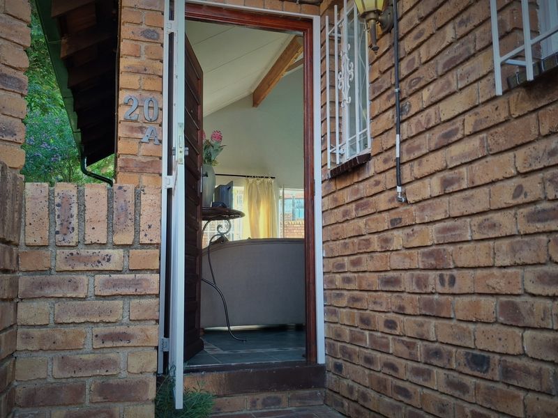 Entrance view of the property featuring a face brick facade, secure door access, and window security bars.