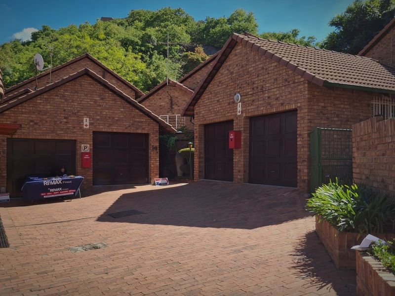 Front exterior view of a cluster property featuring face brick facades, tiled roofs, and a paved driveway with multiple garage access points.