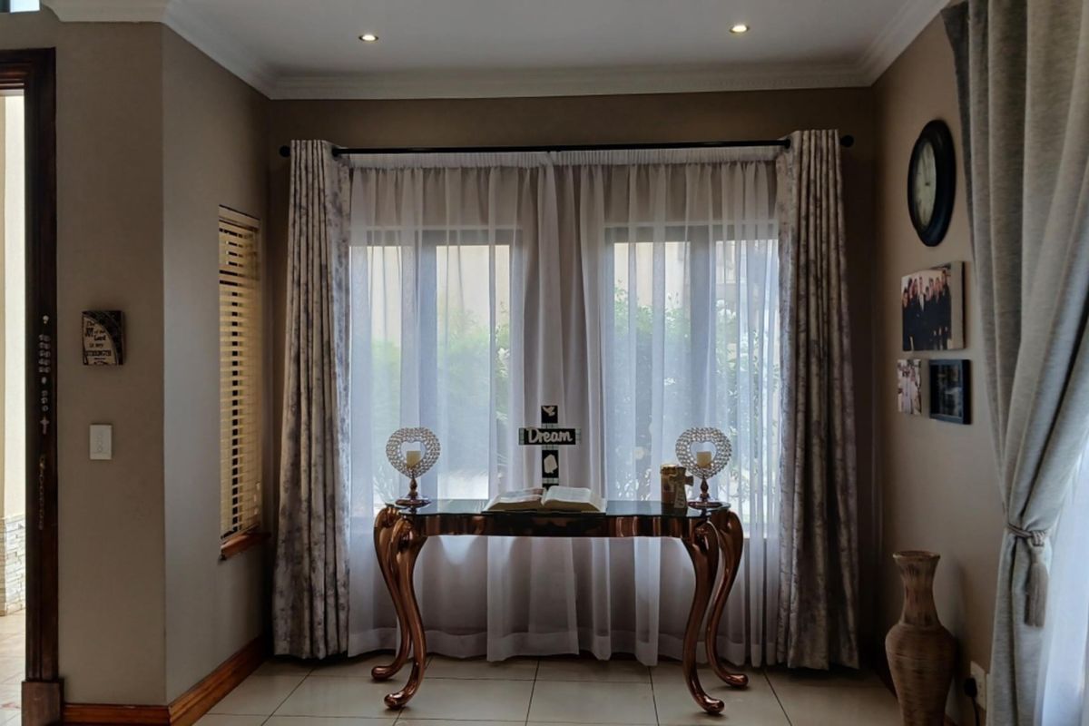 A well-maintained living area featuring tiled flooring, recessed downlighting, and elegant window treatments, creating a warm and inviting atmosphere.