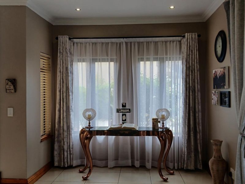 A well-maintained living area featuring tiled flooring, recessed downlighting, and elegant window treatments, creating a warm and inviting atmosphere.