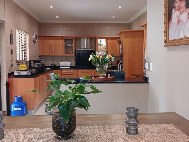 A functional kitchen featuring wooden cabinetry, granite countertops, and a tiled backsplash, with an open-plan layout connecting to the dining area.