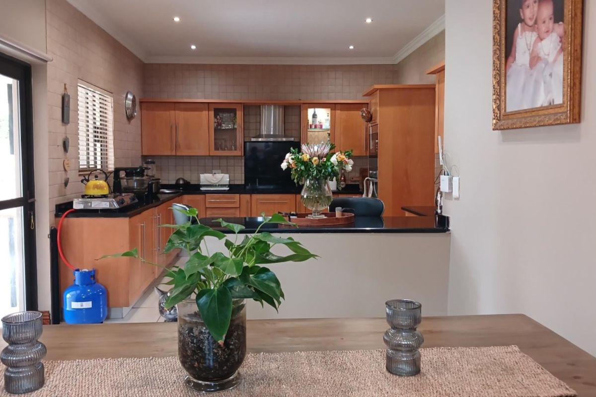 A functional kitchen featuring wooden cabinetry, granite countertops, and a tiled backsplash, with an open-plan layout connecting to the dining area.