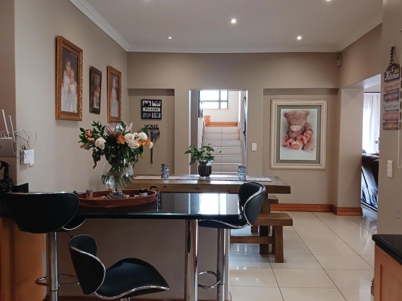 Open-plan kitchen and dining area featuring granite countertops, tiled flooring, and recessed lighting, creating a functional and connected living space.
