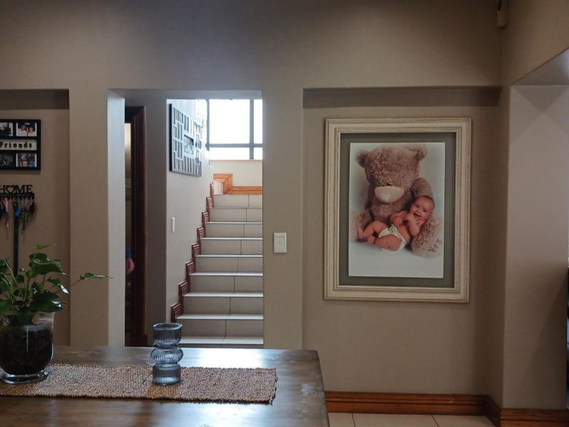 A view of a residential hallway featuring a tiled staircase and neutral wall finishes, providing access to other areas of the home.