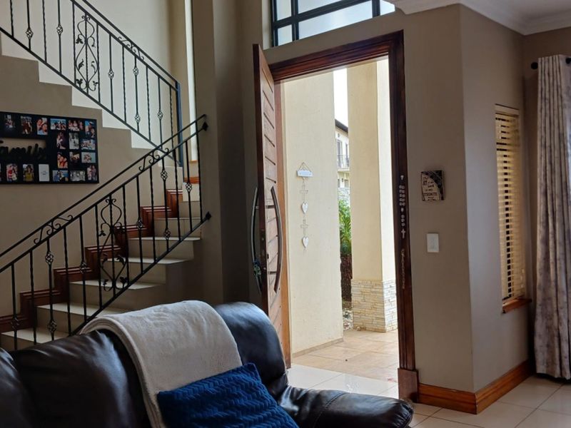 Welcoming entrance area featuring a tiled floor, a decorative wrought iron staircase railing, and a solid timber front door with a transom window.