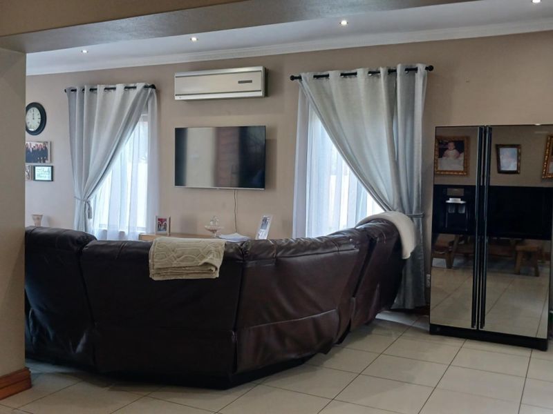 A comfortable living room featuring tiled flooring, recessed ceiling lighting, and a wall-mounted split-system air conditioning unit.