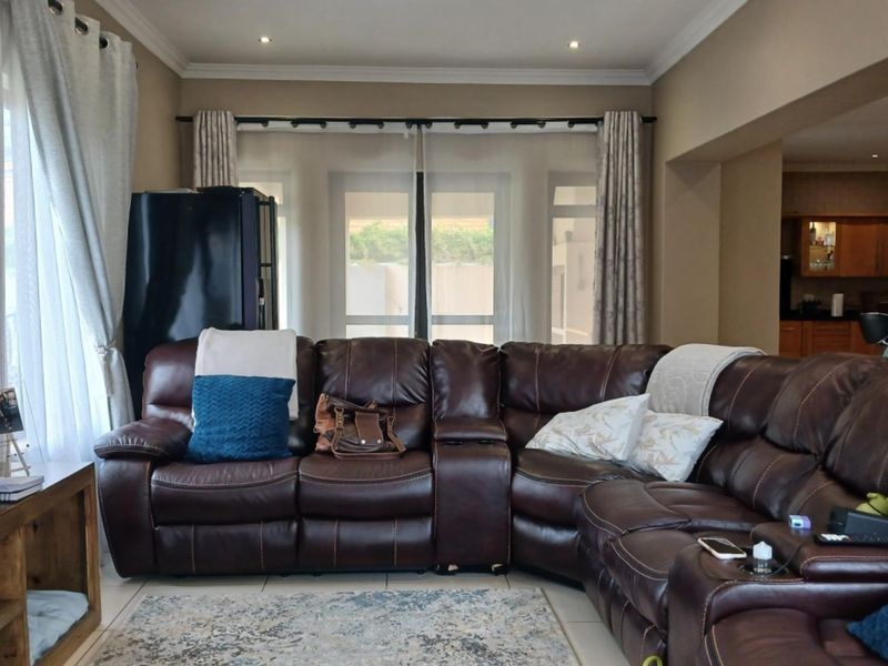 A comfortable living room featuring tiled flooring, recessed downlighting, and sliding glass doors that provide natural light and access to the outdoor area.
