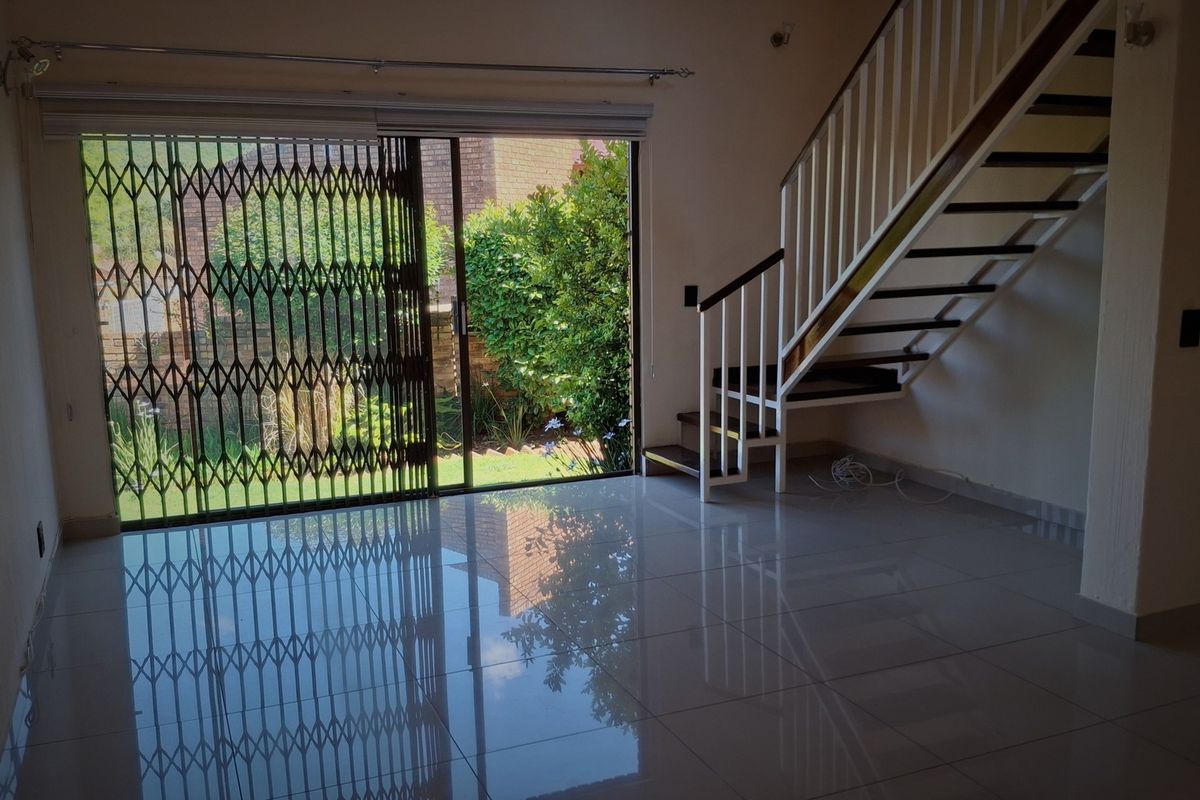 Spacious open-plan living area featuring polished tile flooring, a modern staircase, and large sliding doors providing direct access to the private garden.