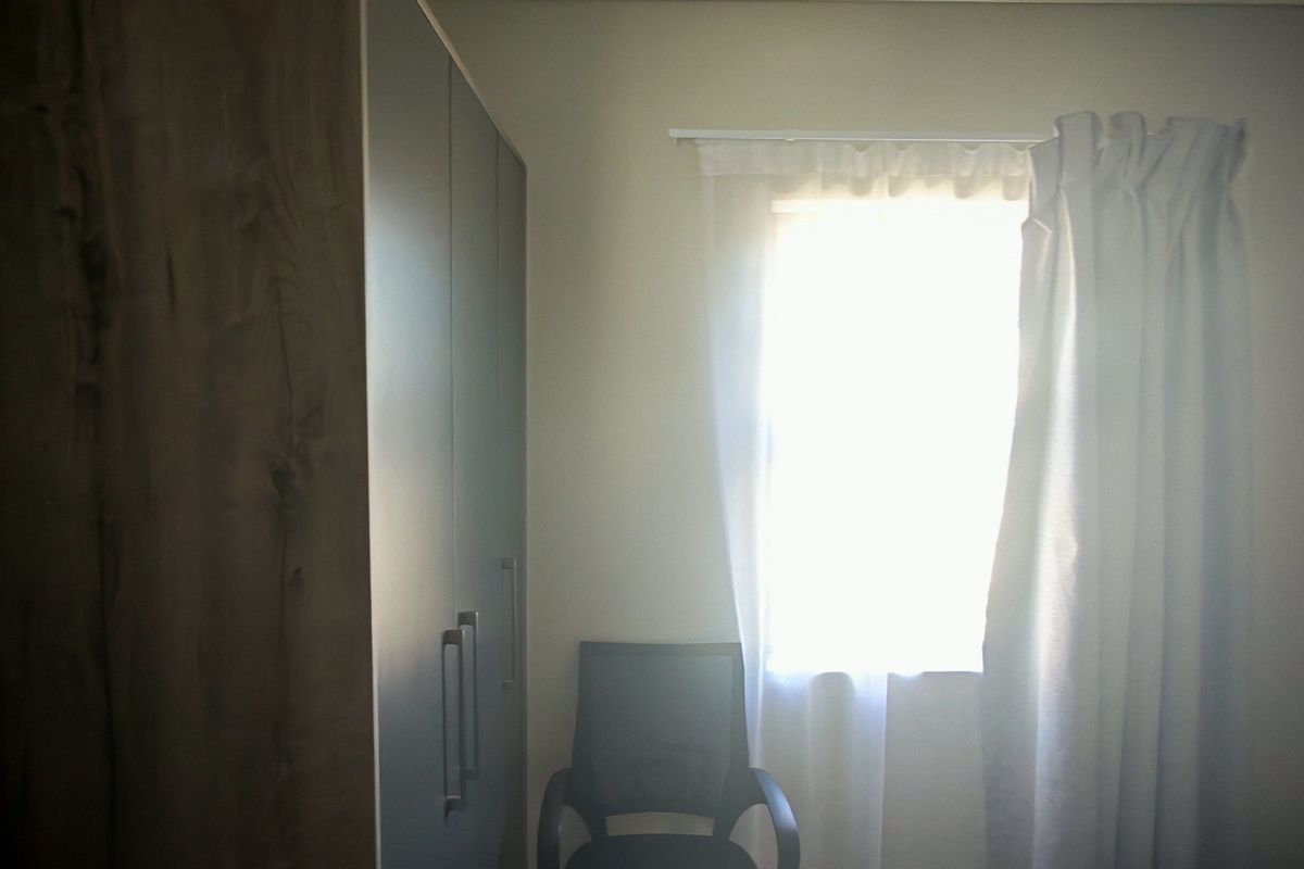 A bedroom featuring built-in cupboards and a window with natural light.
