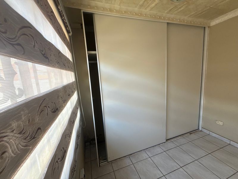 A bedroom featuring tiled flooring and a built-in sliding wardrobe with visible maintenance issues requiring repair.